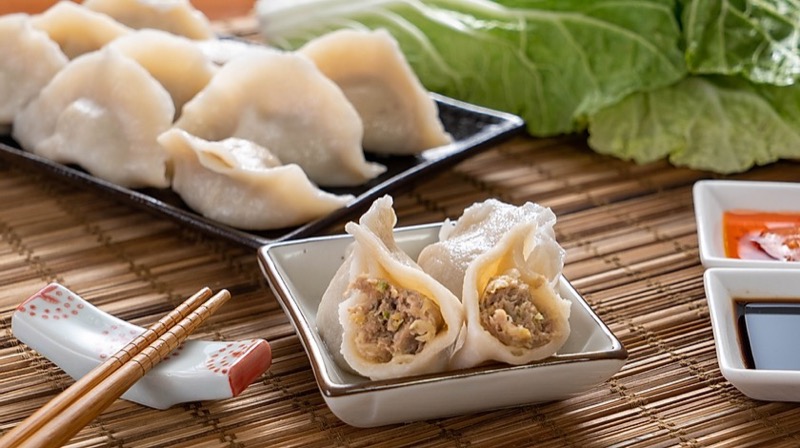 Plump boiled dumplings cut open showing fresh pork and vegetable filling