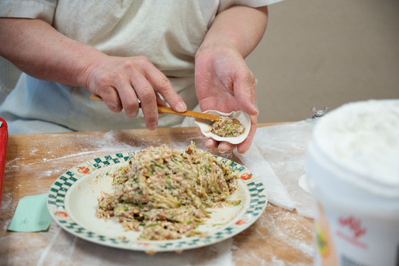 Close-up of dumpling being filled with savory filling